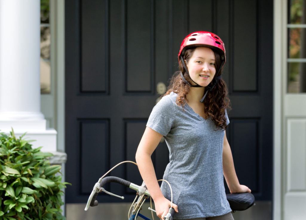 Teenage Girl wearing helmet while resting on bicycle outdoors
